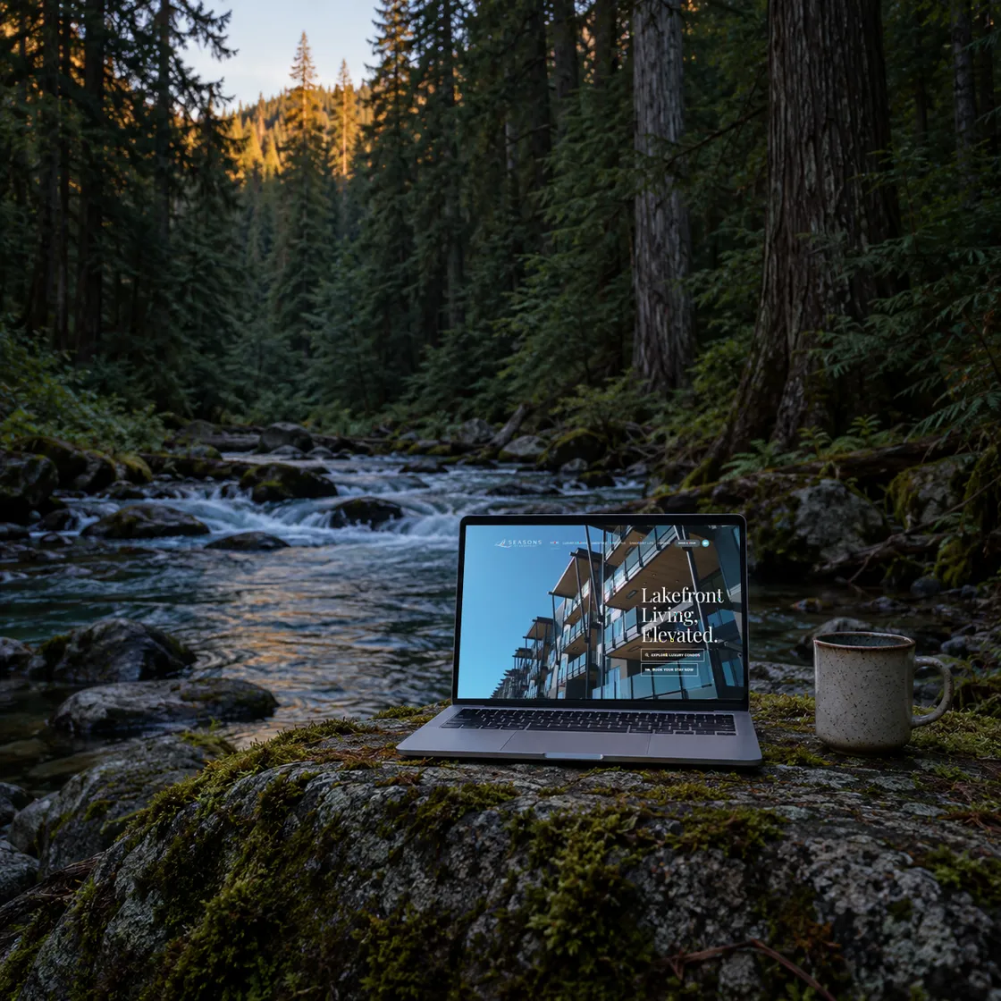 A laptop on a cedar slab by a mountain stream, showing a website built by Cedar Stream Media